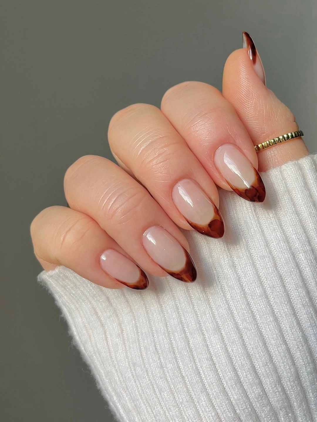 Medium almond pale nails with warm brown-red outlined tips