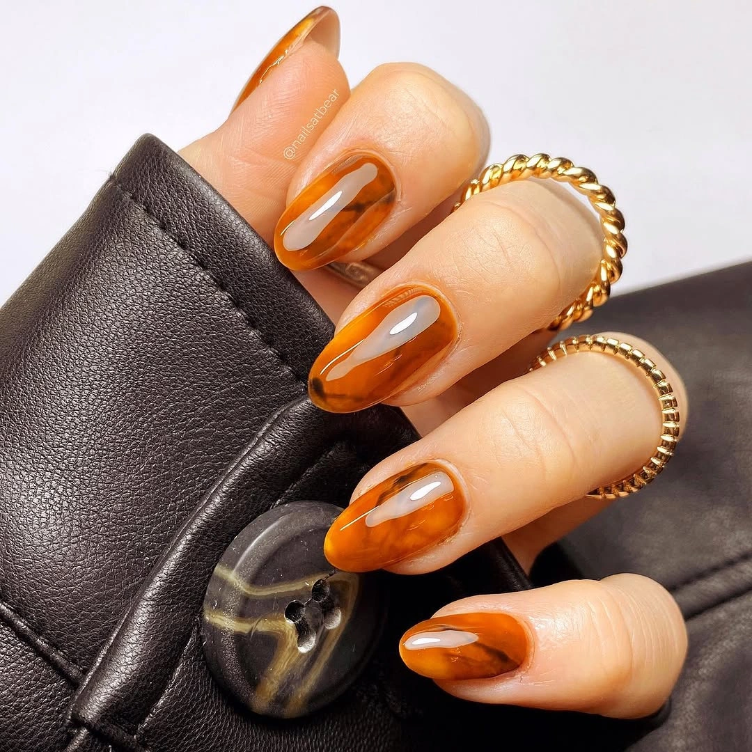 Long almond nails with glossy orange color and dark outlined tips