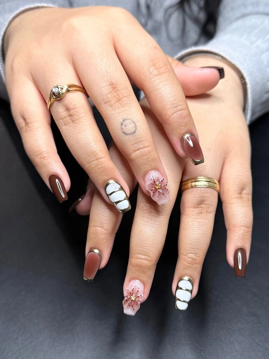 medium brown coffin nails with pale lines and a small floral accent