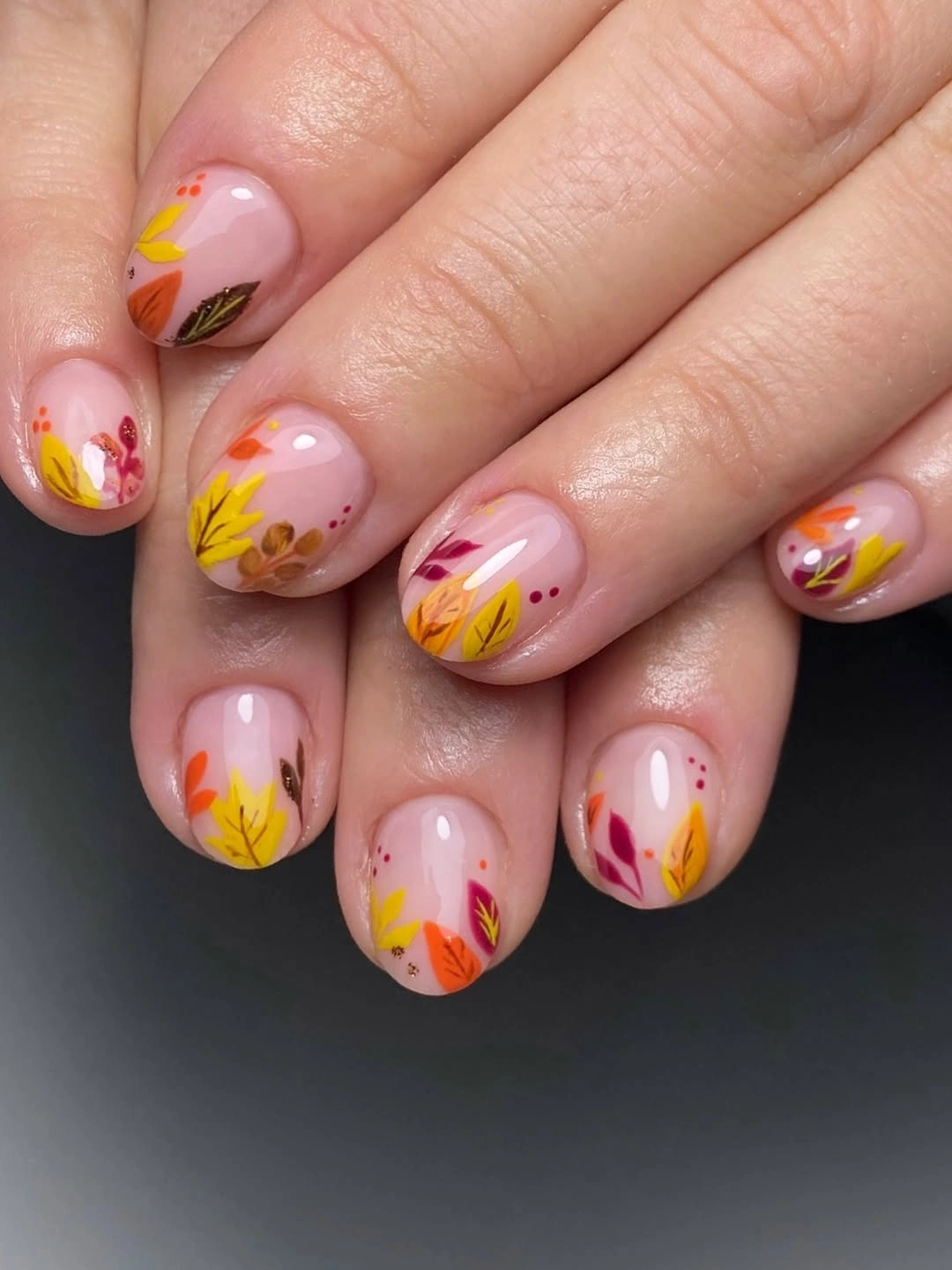 Rounded nude nails with tiny autumn leaf art