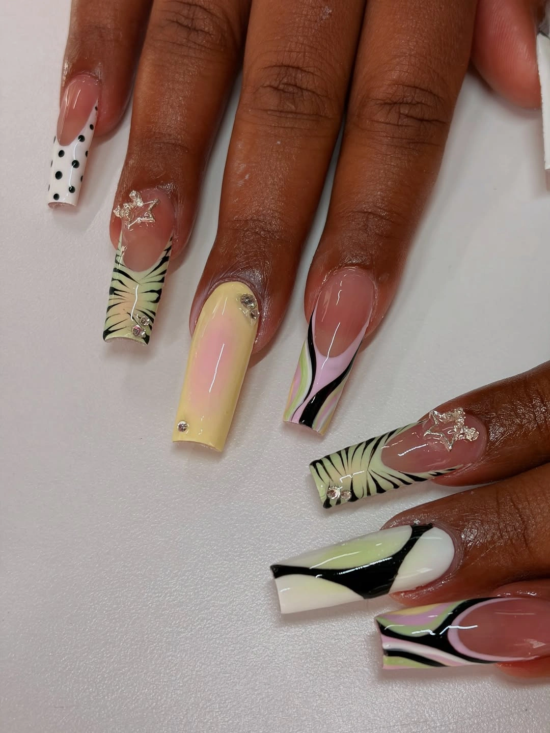 Long nude square nails with freeform olive yellow pink and black abstract details