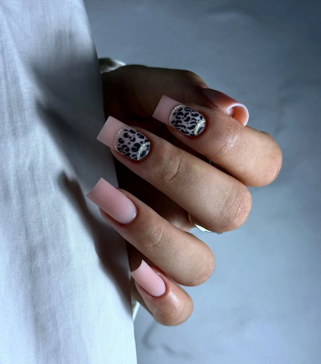 Short pale pink square nails with compact black and white animal-print accents