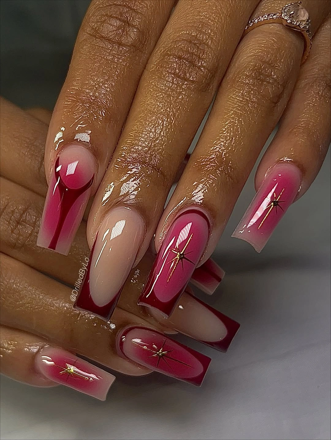 Long nude square nails with fuchsia blocks and small gold starburst accents