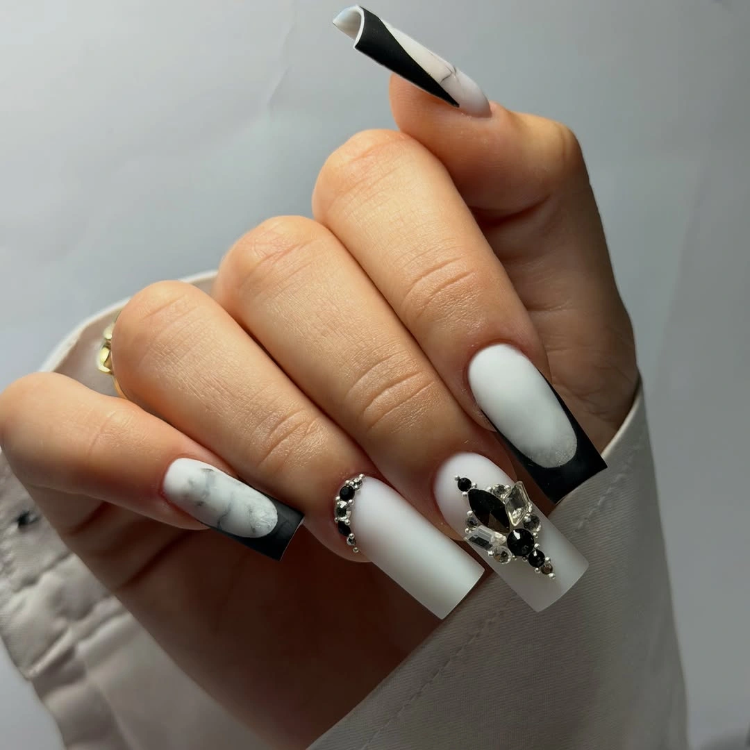 Milky white square nails with diagonal black tips and graphic accents