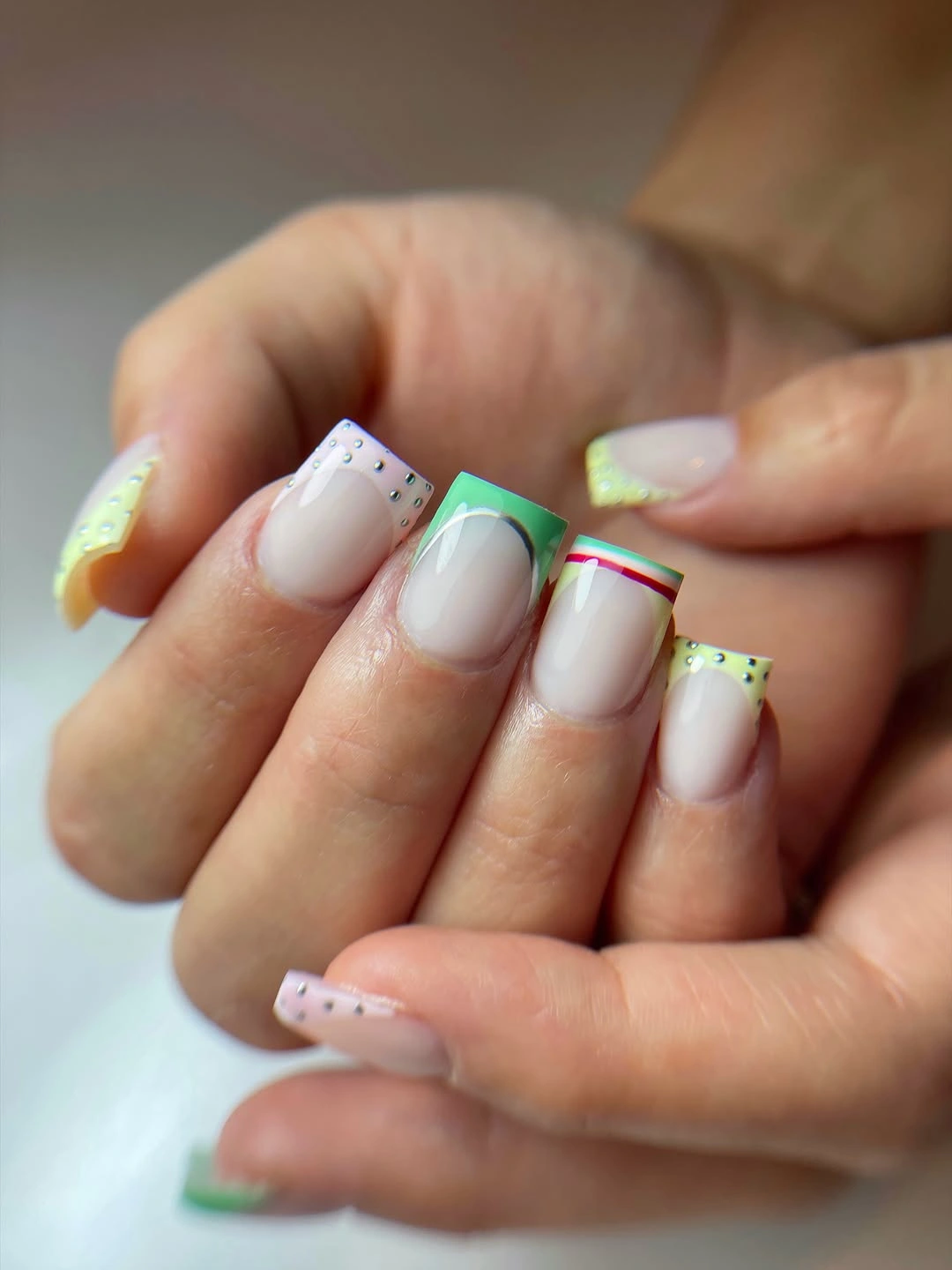 Pale short square nails with thin green and pink outline French tips