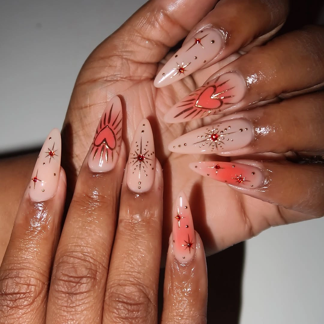 Long pink almond nails with sparse multicolor rhinestone accents