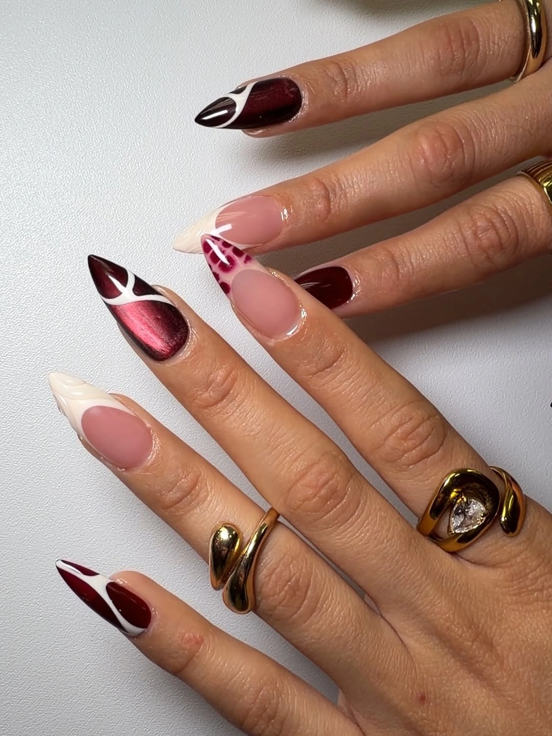 Long blush almond nails with red floral linework and tiny starbursts