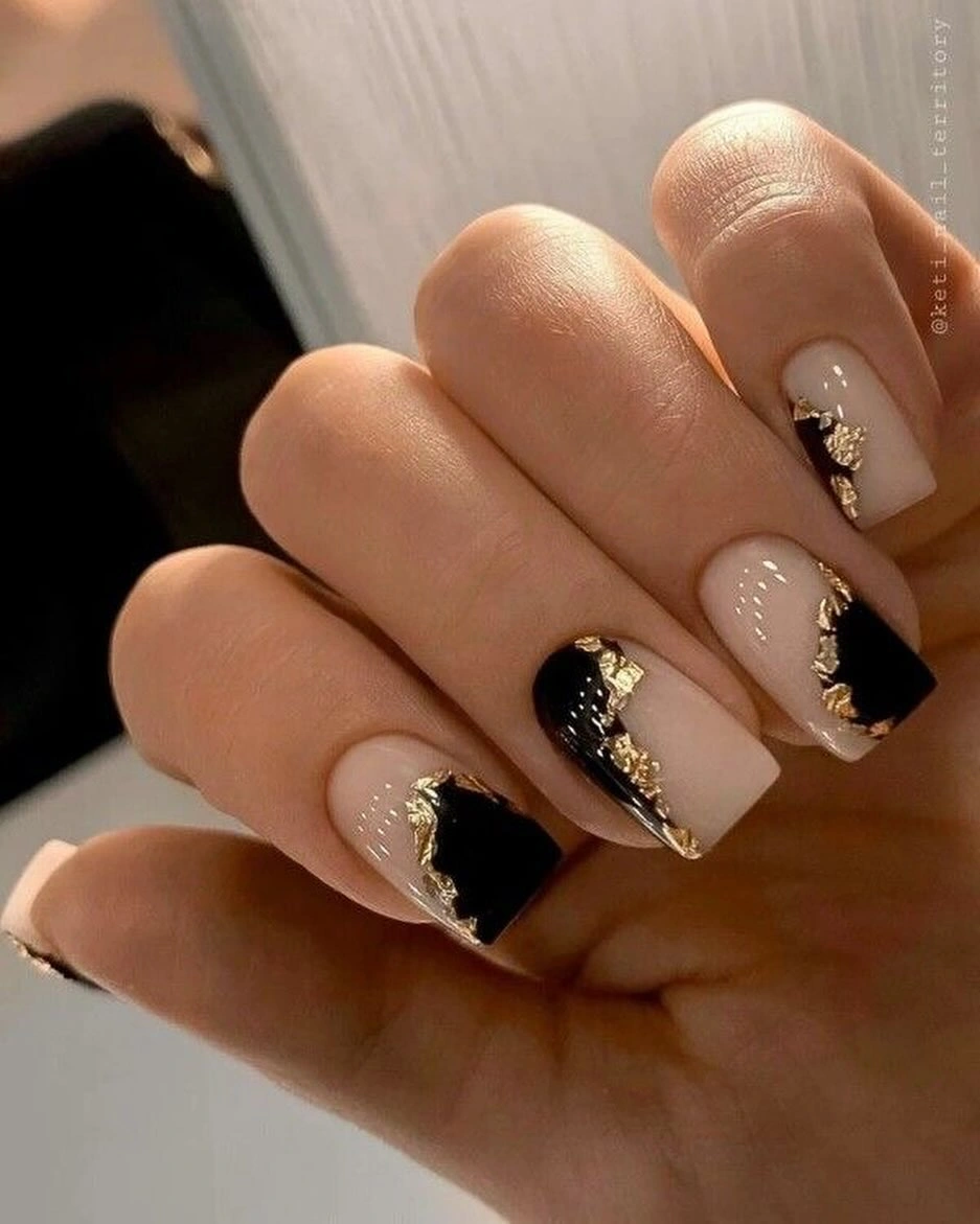 Long nude almond wedding nails with black French tips and gold accents