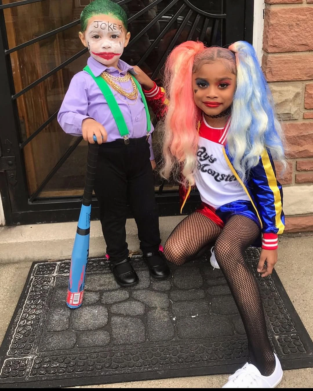 Children dressed as Joker and Harley Quinn with purple green costume red blue jacket fishnet tights two-tone hair and toy mallet