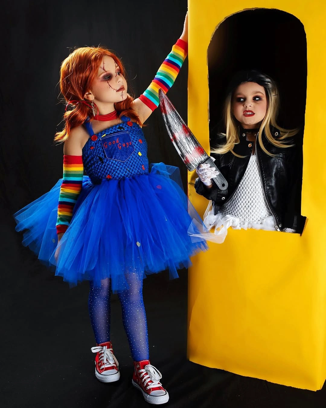 Children dressed as Chucky with blue overalls rainbow sleeves and M3GAN in black-and-white doll dress