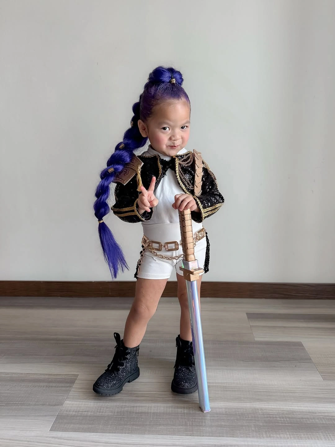 Child in fantasy dragon-slayer warrior costume with black and gold jacket purple braid arm guard and toy sword