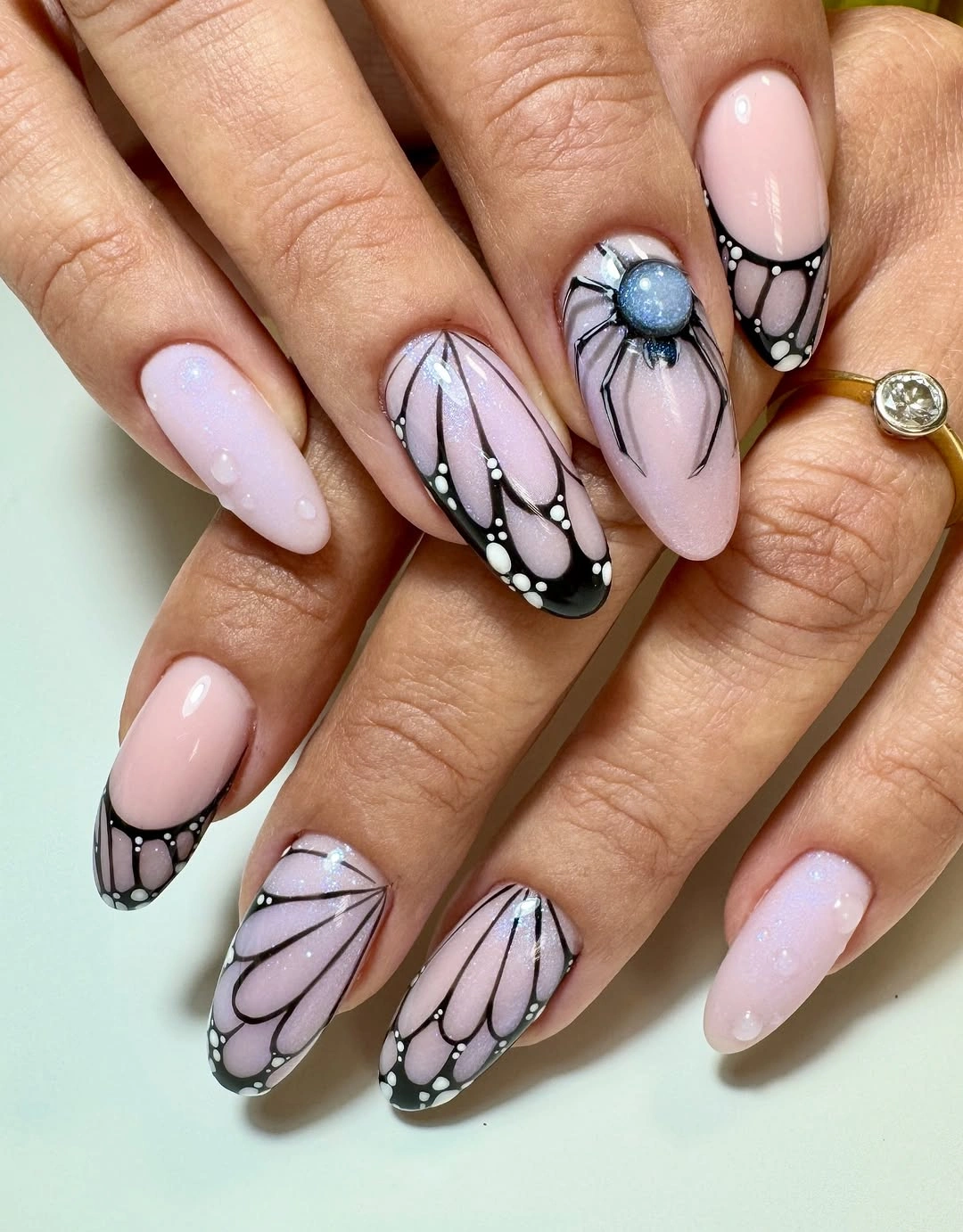 Medium almond pale pink nails with repeated black outlined pointed motifs
