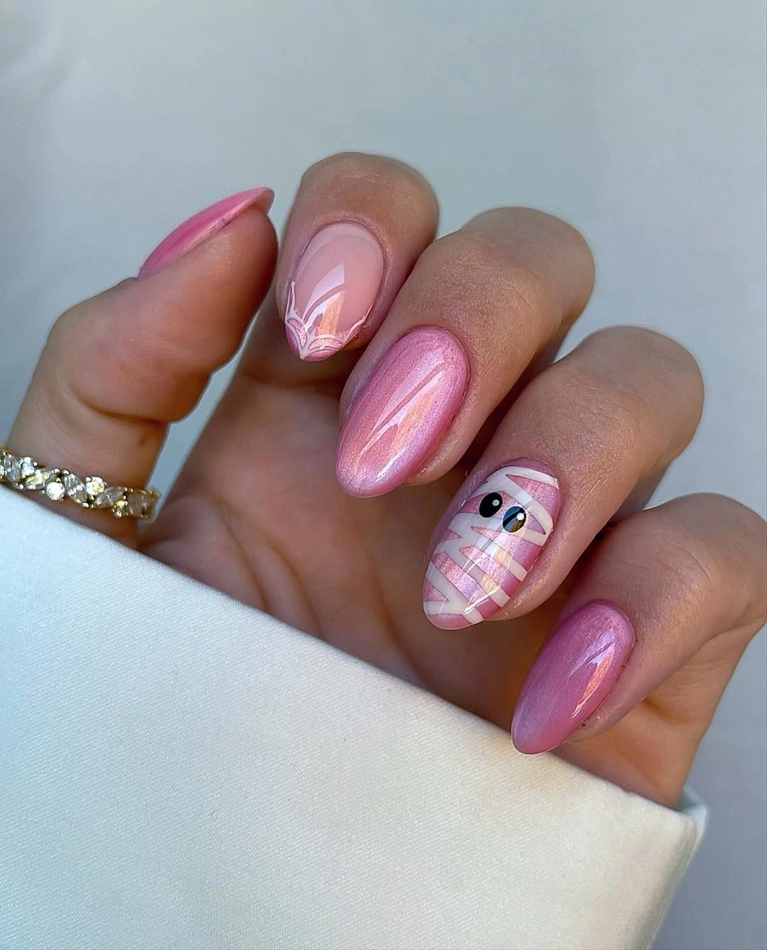 Glossy pink almond nails with one tiny pale Halloween accent