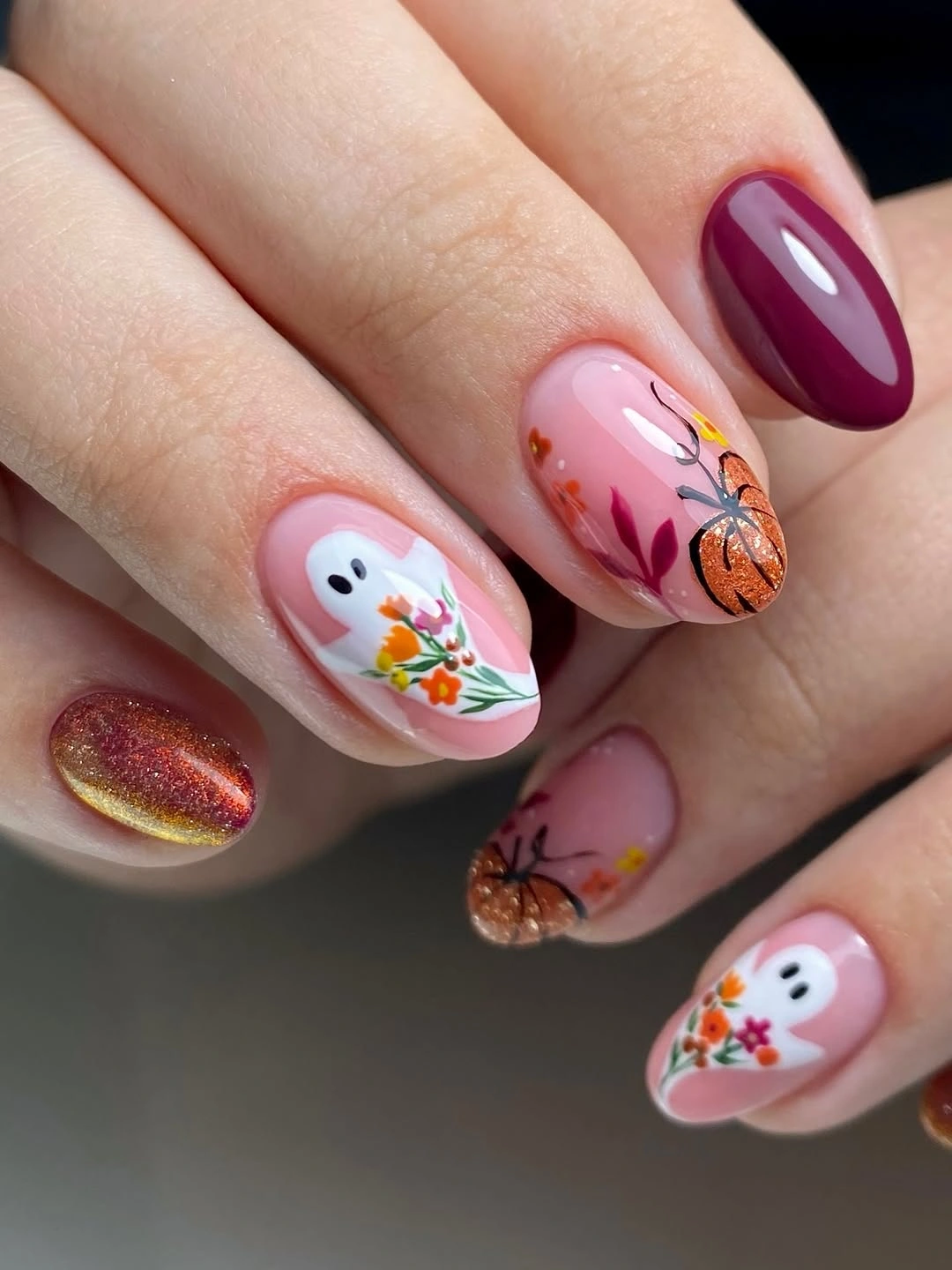 Short pink nails with white ghost and orange seasonal accents