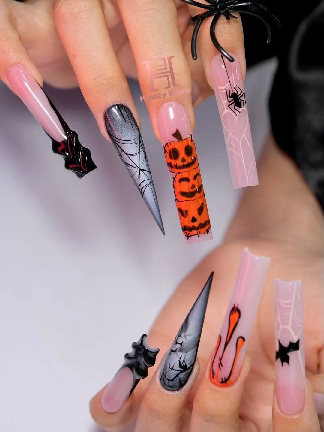 Long pink stiletto nails with one orange character accent and dark details
