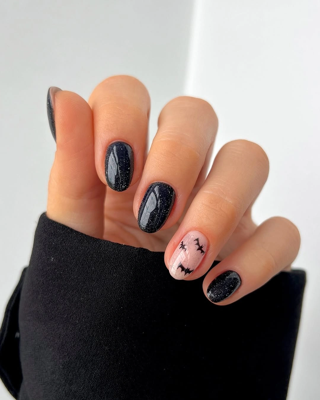 Short black and nude nails with a tiny pink seasonal accent