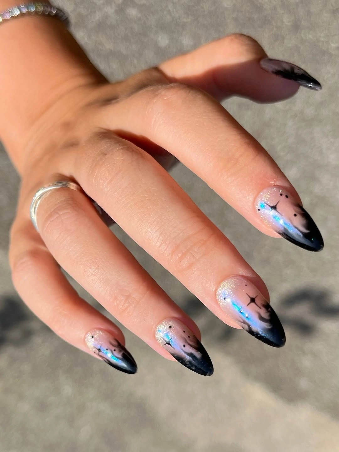 Long pale almond nails with dark pointed tips and small accents