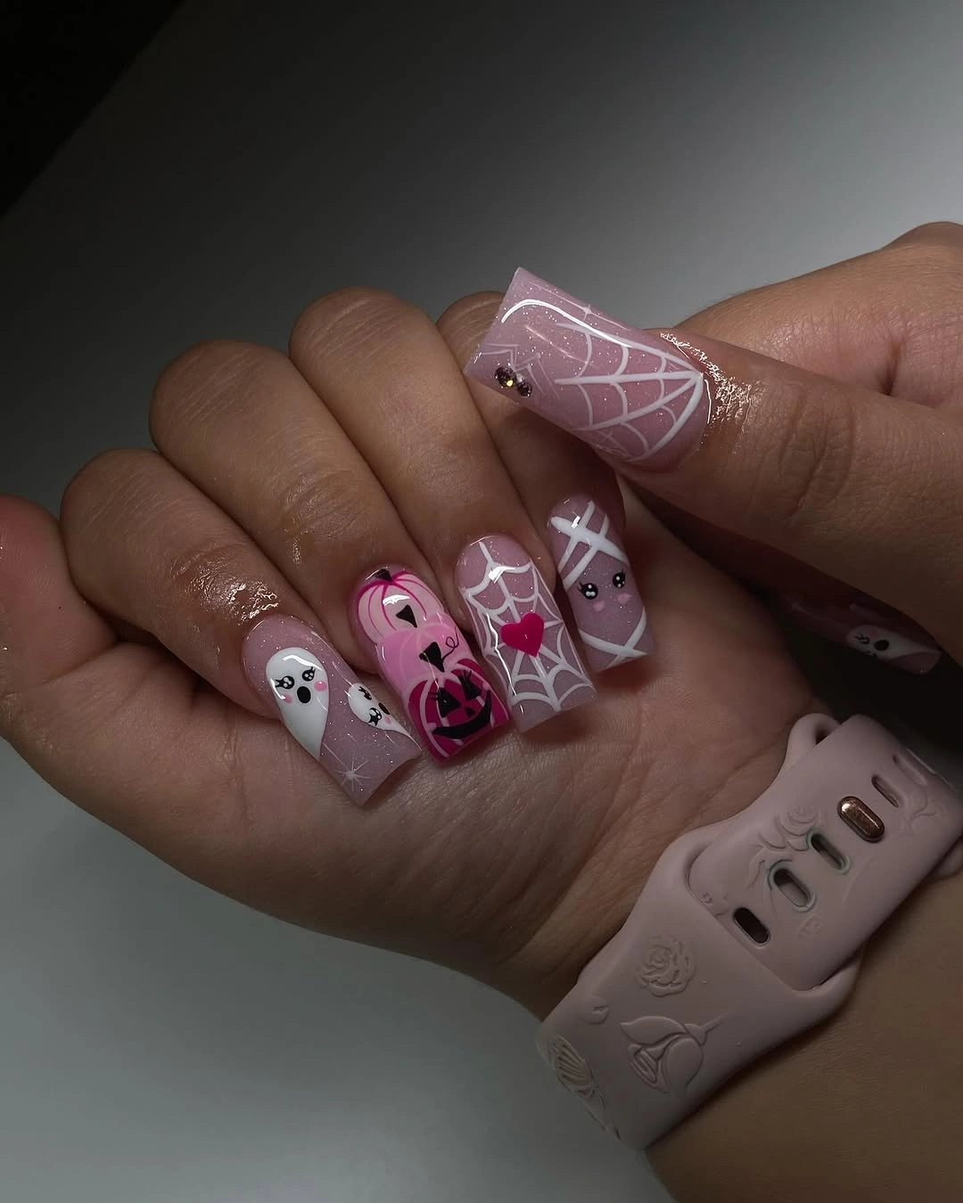 Pink and mauve almond nails with pale web lines and spooky motifs