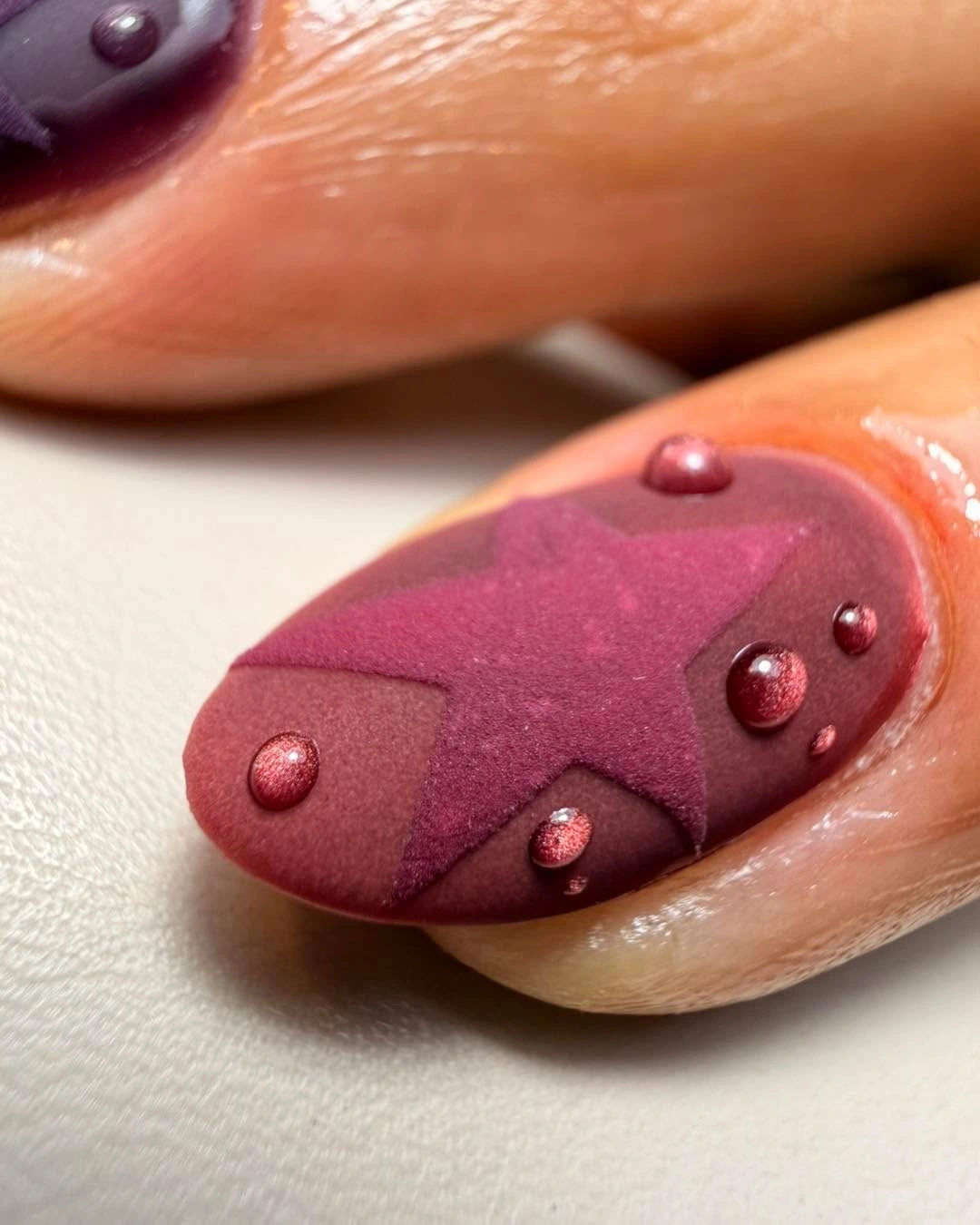 Dusty plum nail with raised looking burgundy star and round details