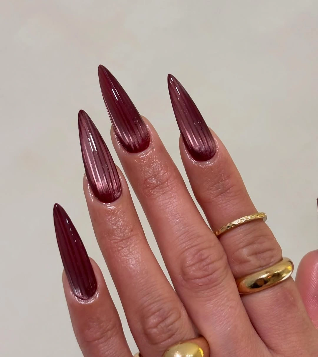 Long burgundy stiletto nails with fine pale vertical pin lines