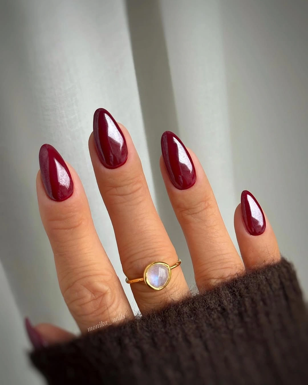 Glossy medium almond nails in a bright cherry maroon shade