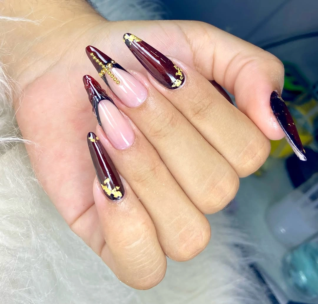 Long coffin nails with maroon nude black and gold colored accents