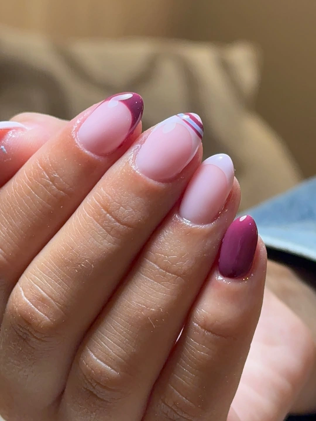 Pale pink almond nails with thin berry and white tip lines