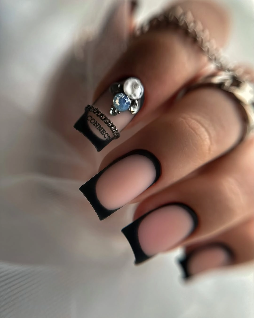 Short blush square nails framed with bold black tips and borders