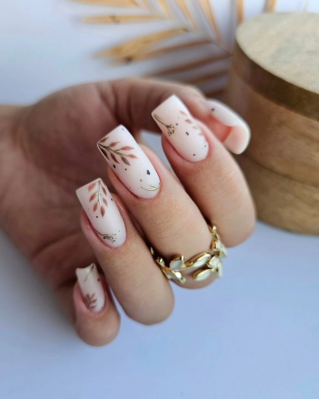Short white square nails with delicate brown and green botanical line art