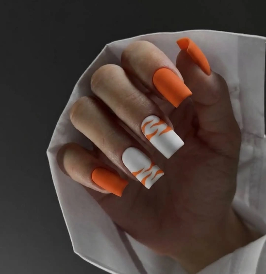 Long orange square nails with white nails and orange wavy lines