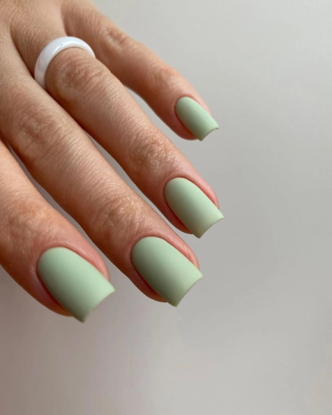 Short softly squared nails in muted sage green