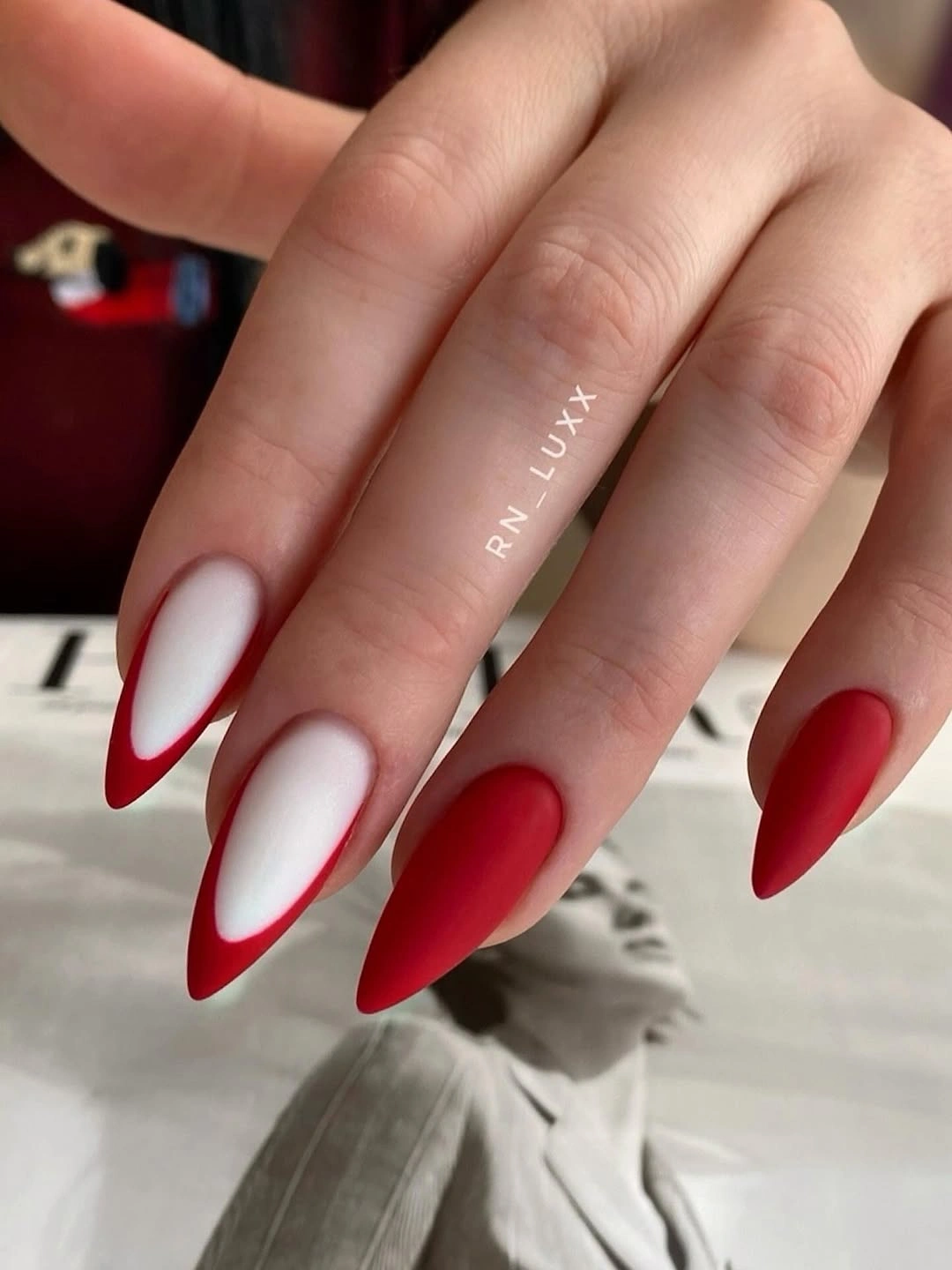 Milky almond nails with deep red outlined tips and accent nail