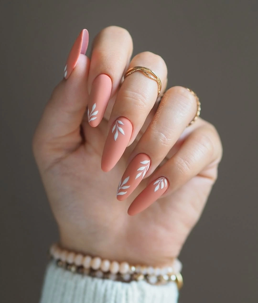 Pale pink almond nails with repeated thin white crescent accents