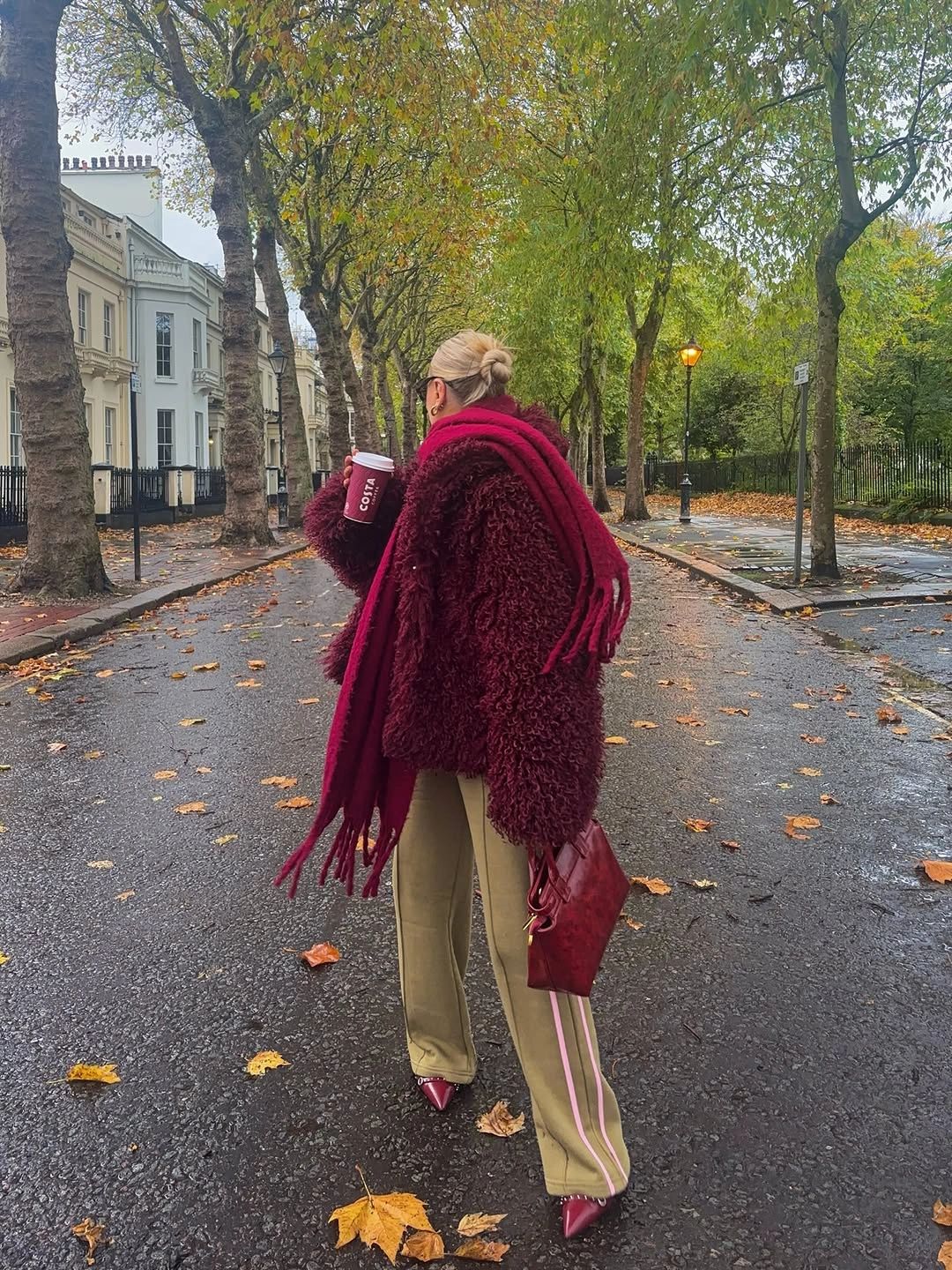 Long burgundy fringed wrap over pale relaxed trousers with matching small bag