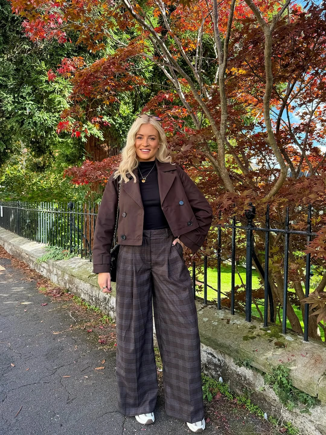 Shaped brown jacket with wide plaid trousers and compact brown shoulder bag