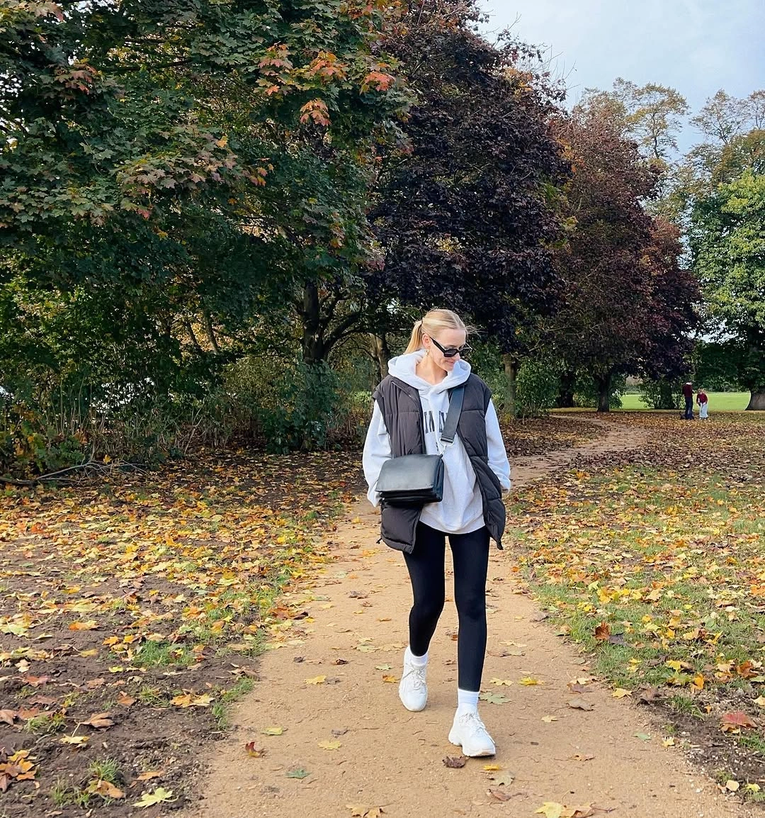 White loose top framed by black sleeveless layer with leggings and white sneakers