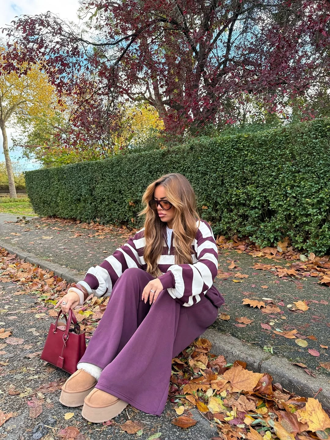 Cream and burgundy striped sweater with wide plum trousers and burgundy handbag