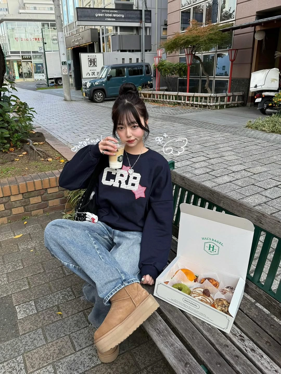 Dark graphic sweatshirt with loose light jeans, tan rounded boots, and black backpack