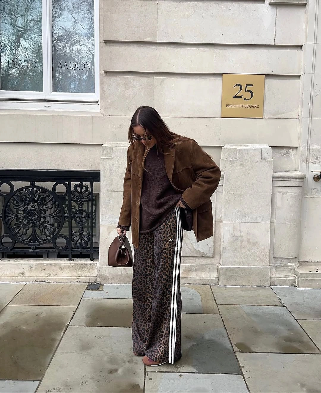 Brown jacket over long black and white patterned skirt or trousers with dark handbag