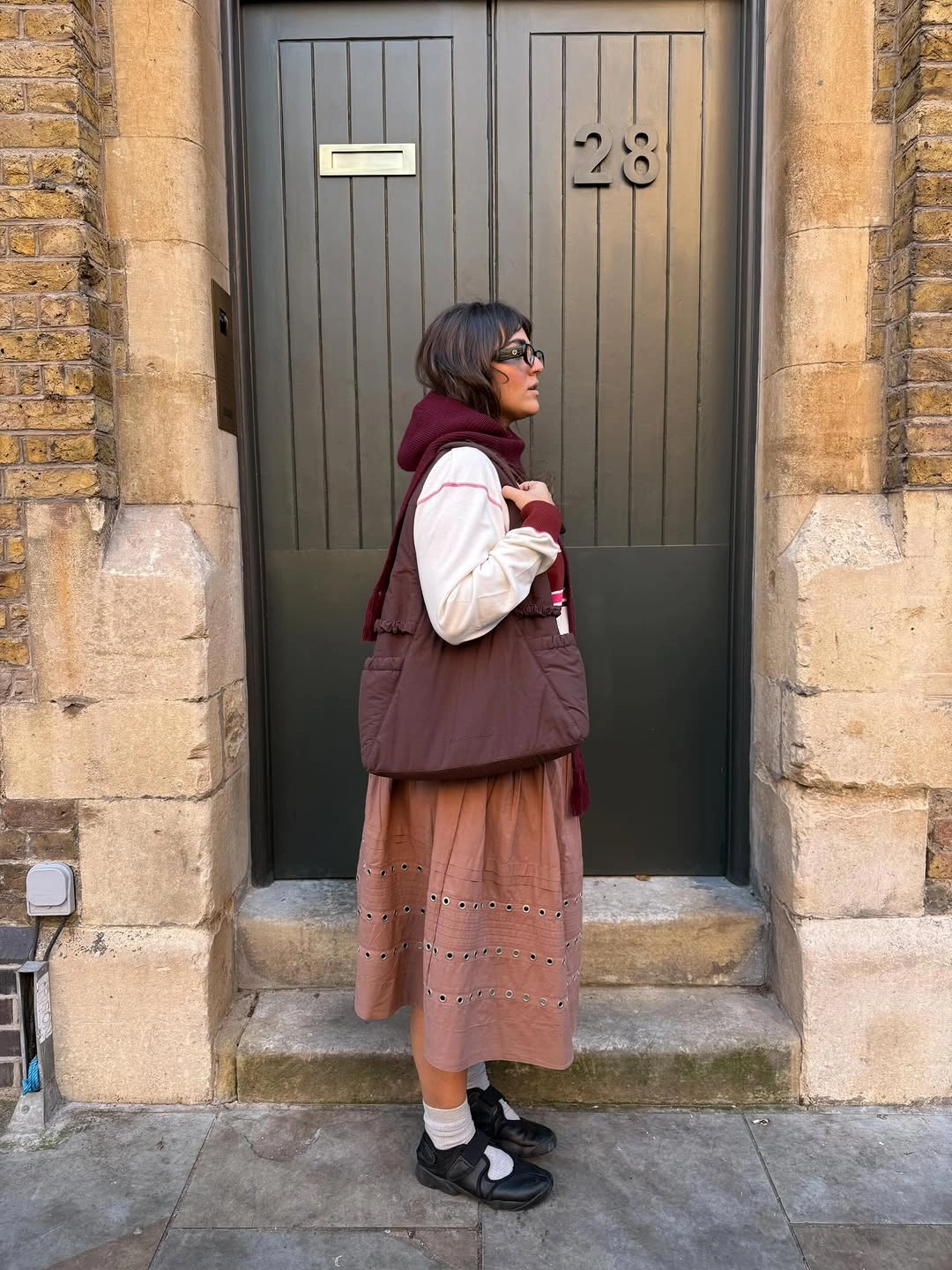 Burgundy quilted vest with dusty pink patterned skirt, white socks, and dark strap shoes