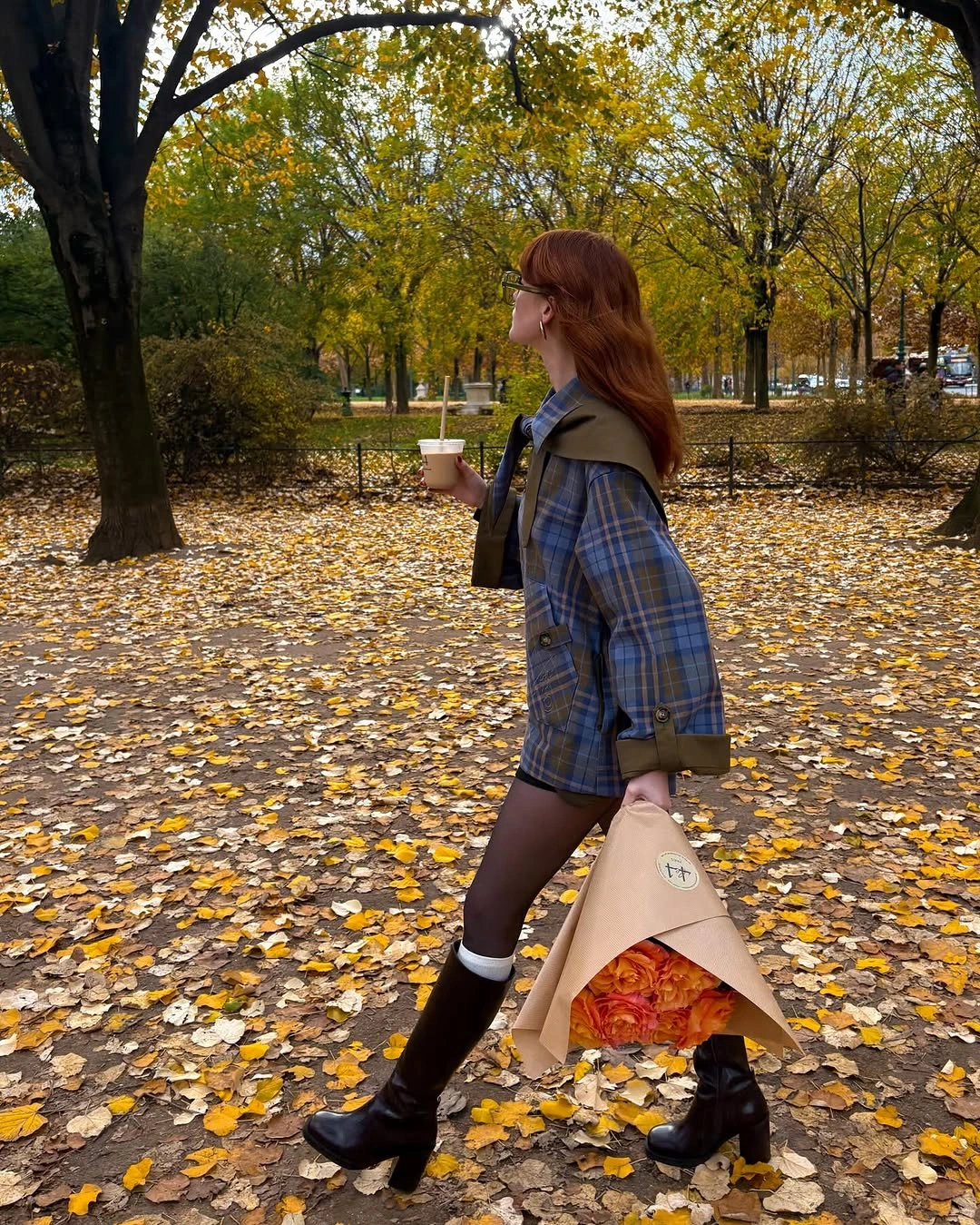 Brown plaid overshirt with dark short skirt, black tights, knee-high boots, and beige tote