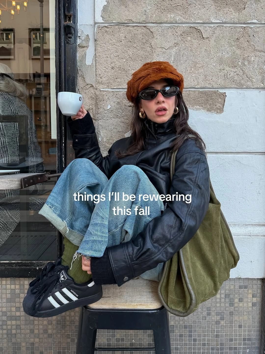 Oversized black jacket with cuffed blue jeans and dark striped sneakers