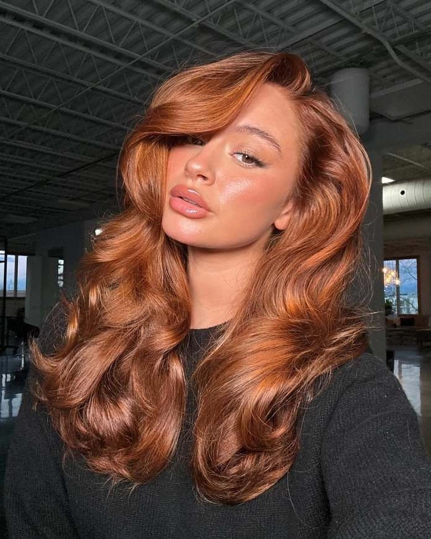 Long copper wavy hair with wide side part and softly reflective-looking finish