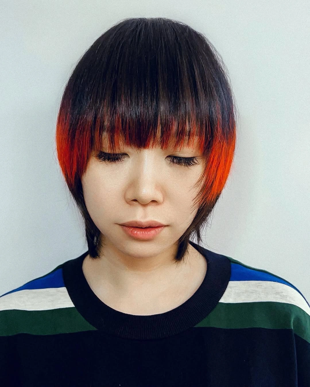 Short black bob with blunt fringe and vivid orange under-panels at front
