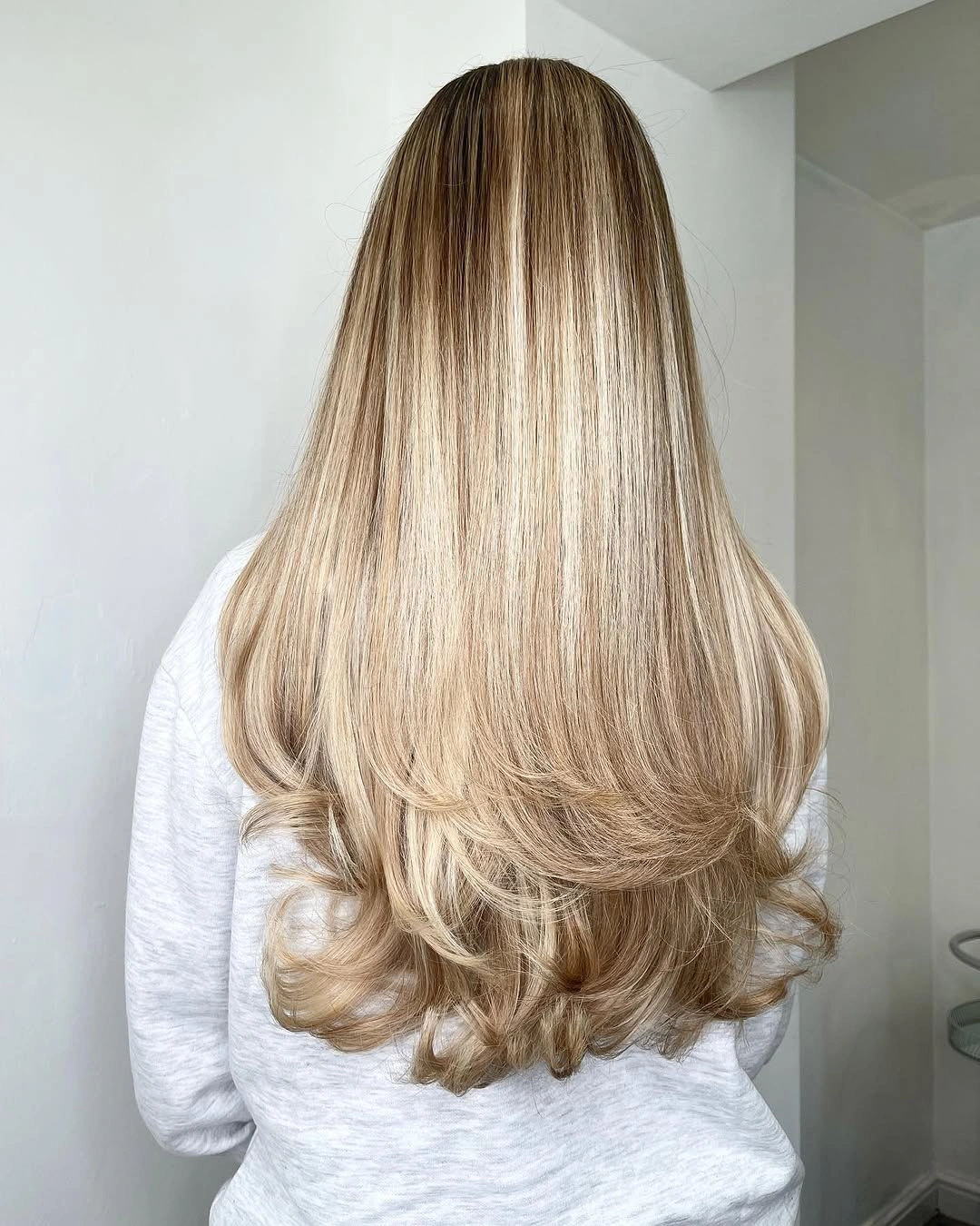 Long creamy blonde hair with soft root depth and curled ends