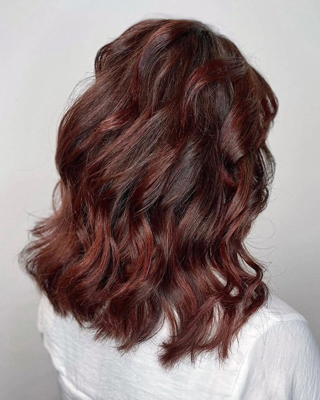 Long deep auburn wavy hair with darker root depth and loose S-waves