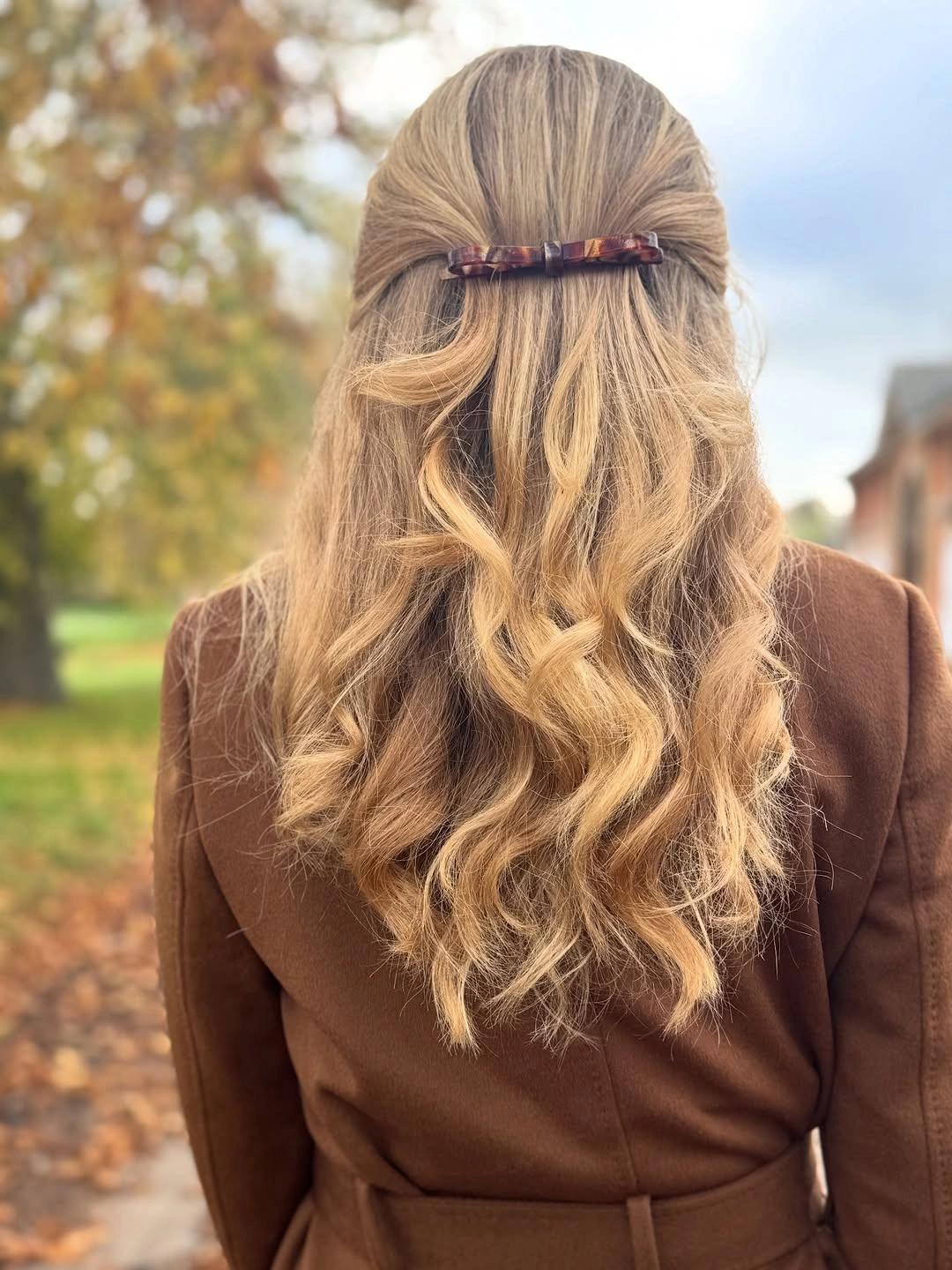 Long golden blonde waves in half-up style with small horizontal barrette