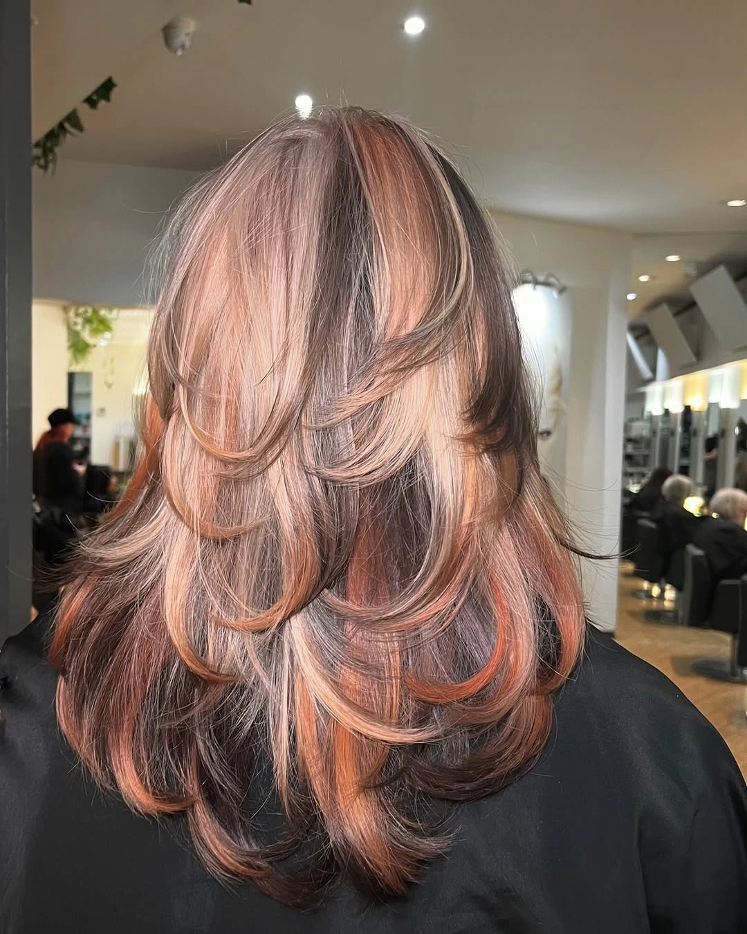 Medium brunette layered haircut with peach-beige front ribbons and soft choppy ends