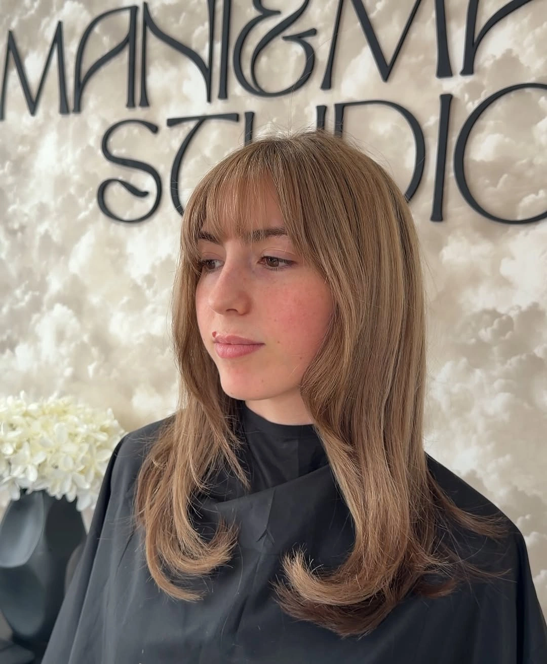 Medium beige-blonde layered haircut with airy long fringe and rounded shoulder-length ends