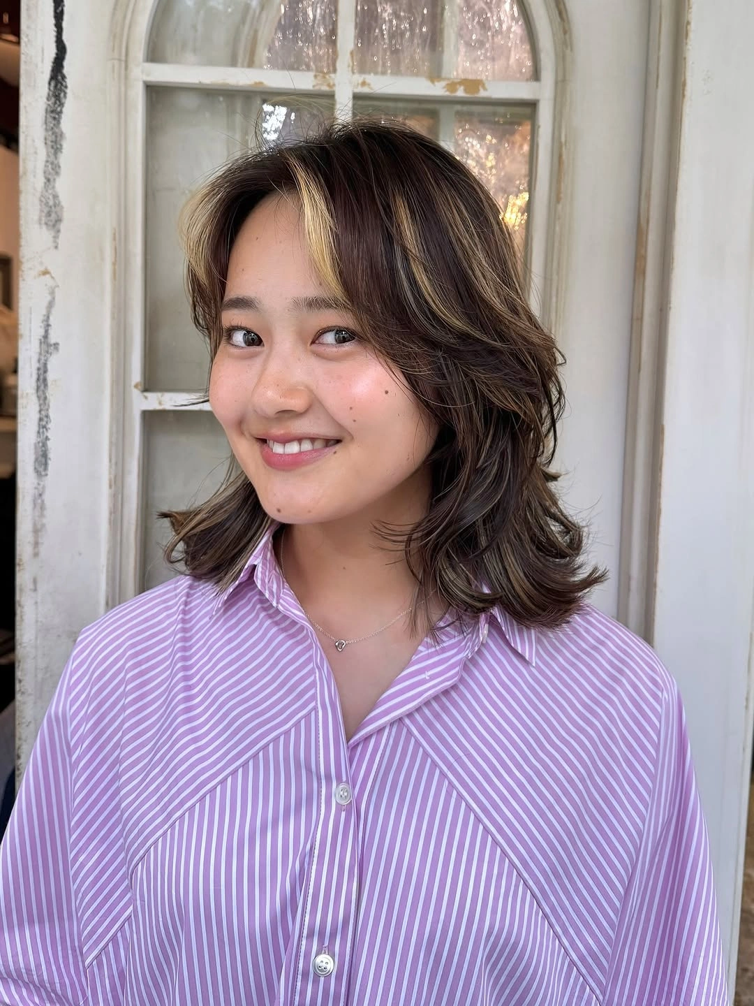 Dark layered shoulder-length lob with cream-beige face frame and flipped ends